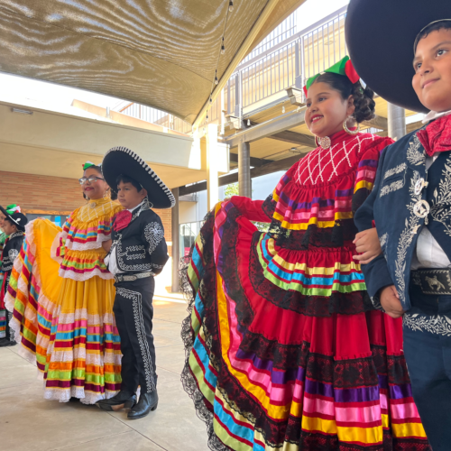 A group of children perform a dance wearing traditional clothing