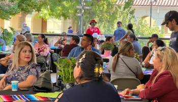 Individuals seated at tables with colorful runners